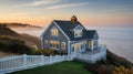 Beautiful Cape Cod house with gray shingle siding overlooking the ocean at sunset Royalty Free Stock Photo