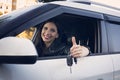 Beautiful car driver woman smiling showing new car keys and car. Caucasian girl sitting in automobile, smiling and demonstrating
