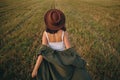 Beautiful carefree woman in hat walking in evening summer field. Relaxing in countryside. Happiness Royalty Free Stock Photo