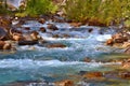 Beautiful cascade mountains stream. Blue river, brown stones in the water, green bushes on the shore. Royalty Free Stock Photo