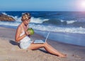 Beautiful casual woman with a laptop on the beach with the sea i Royalty Free Stock Photo