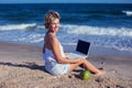 Beautiful casual woman with a laptop on the beach with the sea i Royalty Free Stock Photo