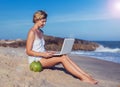 Beautiful casual woman with a laptop on the beach with the sea i Royalty Free Stock Photo