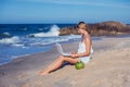 Beautiful casual woman with a laptop on the beach with the sea i Royalty Free Stock Photo