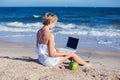 Beautiful casual woman with a laptop on the beach with the sea i Royalty Free Stock Photo