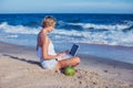 Beautiful casual woman with a laptop on the beach with the sea i Royalty Free Stock Photo