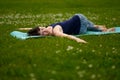 Beautiful caucaisan young woman working out outdoors on blue mat. Jathara Parivartanasana top view Royalty Free Stock Photo