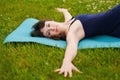 Beautiful caucaisan young woman working out outdoors on blue mat. Jathara Parivartanasana top view Royalty Free Stock Photo