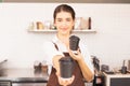 Beautiful caucasian barista woman gives takeaway coffee cups in one hand forward and show one takeaway coffee cup in another hand Royalty Free Stock Photo