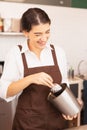 Beautiful caucasian barista woman happy to scoop coffee beans from coffee equipment into coffee bean grinder in cafe coffee shop Royalty Free Stock Photo