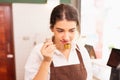 Beautiful caucasian barista woman tests coffee smell after grinding at coffee bar