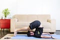 Beautiful caucasian bearded man in black clothes on blue yogamat doing plow pose