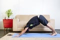 Beautiful caucasian bearded man in black clothes on blue yogamat doing downward facing dog pose