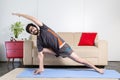 Beautiful caucasian bearded man in black clothes on blue yogamat doing extended side angle pose