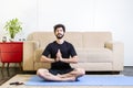 Beautiful caucasian bearded man in black clothes on blue yogamat doing Kali mudra