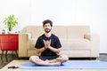 Beautiful caucasian bearded man in black clothes on blue yogamat doing lotus mudra