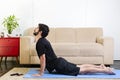 Beautiful caucasian bearded man in black clothes on blue yogamat doing upward-facing dog pose