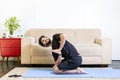 Beautiful caucasian bearded man in black clothes on blue yogamat doing a variation of diamond pose with namaste