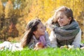 Beautiful caucasian big and little sisters lie on plaid, play with red apples on background of green grass of golden