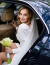 Beautiful caucasian blonde bride sitting in a stylish car with a bouquet Royalty Free Stock Photo