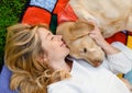Beautiful caucasian blonde girl lying with a white Labrador dog in the garden Royalty Free Stock Photo