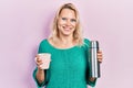 Beautiful caucasian blonde woman drinking a cup of coffee holding thermo smiling with a happy and cool smile on face Royalty Free Stock Photo