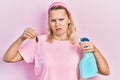 Beautiful caucasian blonde woman holding cockroach and pesticide sprayer clueless and confused expression