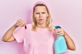 Beautiful caucasian blonde woman holding cockroach and pesticide sprayer depressed and worry for distress, crying angry and afraid Royalty Free Stock Photo