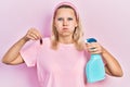 Beautiful caucasian blonde woman holding cockroach and pesticide sprayer puffing cheeks with funny face Royalty Free Stock Photo