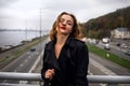 Beautiful Caucasian woman leaning on a bridge over the highway In Winter Time. Royalty Free Stock Photo