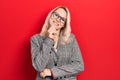 Beautiful caucasian blonde woman wearing business jacket and glasses smiling looking confident at the camera with crossed arms and Royalty Free Stock Photo