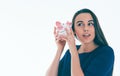 Beautiful Caucasian brunette woman listens to the sound of coinsin a piggybank and dreams. Royalty Free Stock Photo