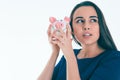 Beautiful Caucasian brunette woman listens to the sound of coinsin a piggybank and dreams. Royalty Free Stock Photo