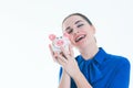 Beautiful Caucasian brunette woman listens to the sound of coinsin a piggybank and dreams. Royalty Free Stock Photo