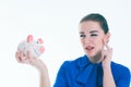 Beautiful Caucasian brunette woman listens to the sound of coinsin a piggybank and dreams. Royalty Free Stock Photo