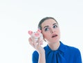 Beautiful Caucasian brunette woman listens to the sound of coinsin a piggybank and dreams. Royalty Free Stock Photo