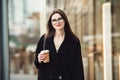 Beautiful caucasian business woman walking to the office on city street with coffee cup wearing glasses. Royalty Free Stock Photo