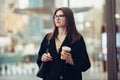 Beautiful caucasian businesswoman walking to the office on city street with coffee cup wearing eyeglasses. Royalty Free Stock Photo