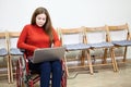 Beautiful Caucasian disabled woman sitting wheel chair and works with laptop indoor