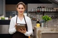 Beautiful Caucasian female barista using tablet and smiling inside coffee shop Royalty Free Stock Photo