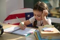 Beautiful Caucasian kid, schoolgirl, first grader sitting on a chair with American flag, using pencil learns writing