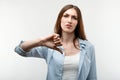 Pretty young woman with long chestnut hair is showing thumb down. Unlike, dislike, failure gestures concept Royalty Free Stock Photo