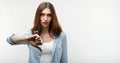 Beautiful caucasian girl with long chestnut hair, dressed in casual clothes, looking is upset at the camera, holding thumb down. Royalty Free Stock Photo