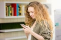 Beautiful caucasian girl with long curly blond hair is using her Royalty Free Stock Photo