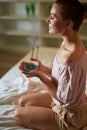 Beautiful caucasian girl meditating while sitting on bed with burning aroma incense sticks