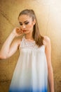 Beautiful Caucasian girl with ponytail and white dress, touching