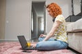 Beautiful caucasian girl sitting on the floor on the carpet at home, use a laptop. Study and work.