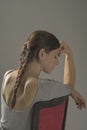 Beautiful caucasian girl slouching on chair - gray background with copy space