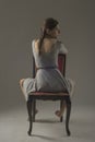 Beautiful caucasian girl slouching on chair - gray background with copy space