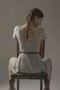 Beautiful caucasian girl slouching on chair - gray background with copy space